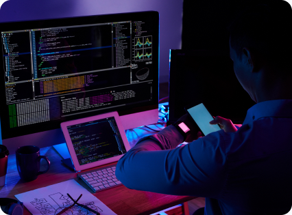 A developer reviewing code on screen at a desk at night